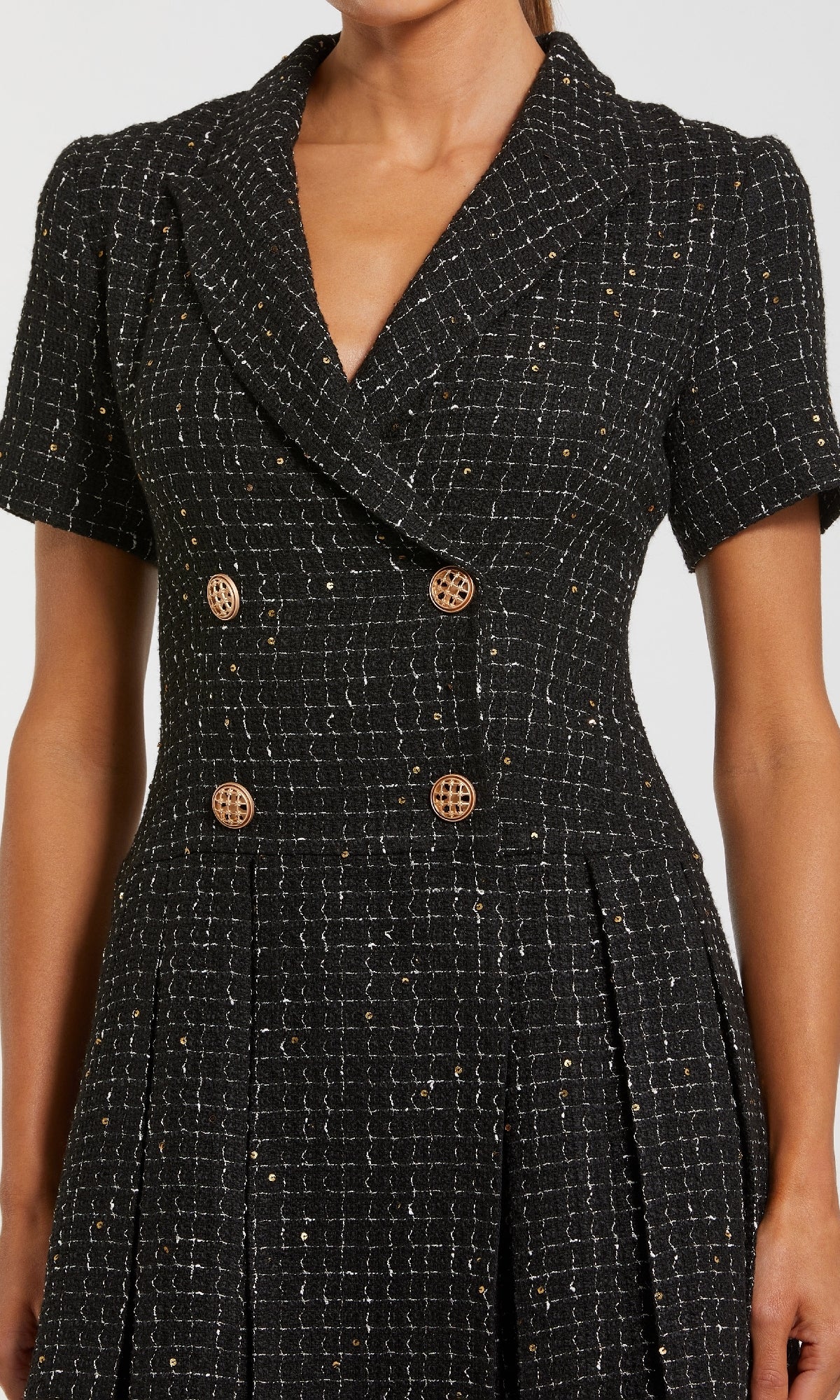 A person wears the Mac Duggal 81200 Tweed-Blazer Short Party Dress—black tweed, short sleeves, double-breasted with gold buttons—making it ideal for any semi-formal occasion.